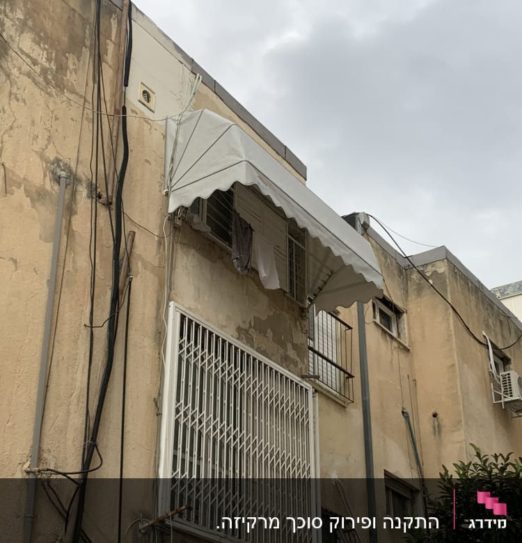 סוכך לבן תלוי מעל חלון בבניין ישן